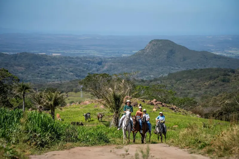 Guests riding horses through green hills near Rincón de la Vieja volcano in Guanacaste